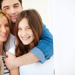 Parents and daughter Portrait of affectionate family of three looking at camera with smiles in isolation